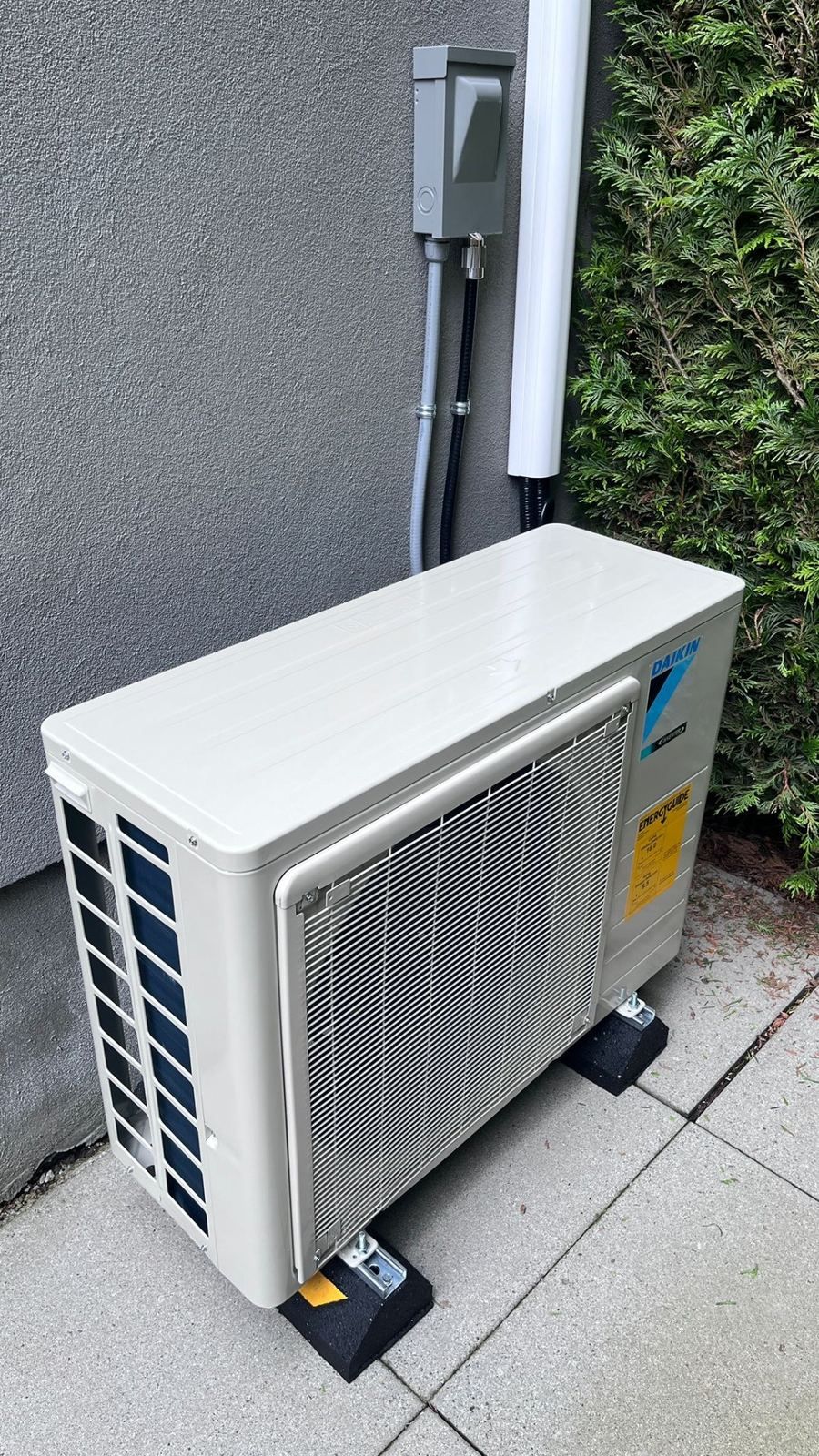 Daikin ductless mini-split outdoor condenser installed on vibration pads with line set cover — Metro Vancouver