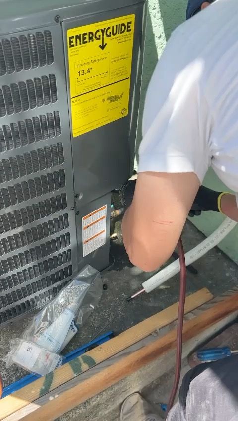 Technician connecting refrigerant lines to Goodman outdoor condenser