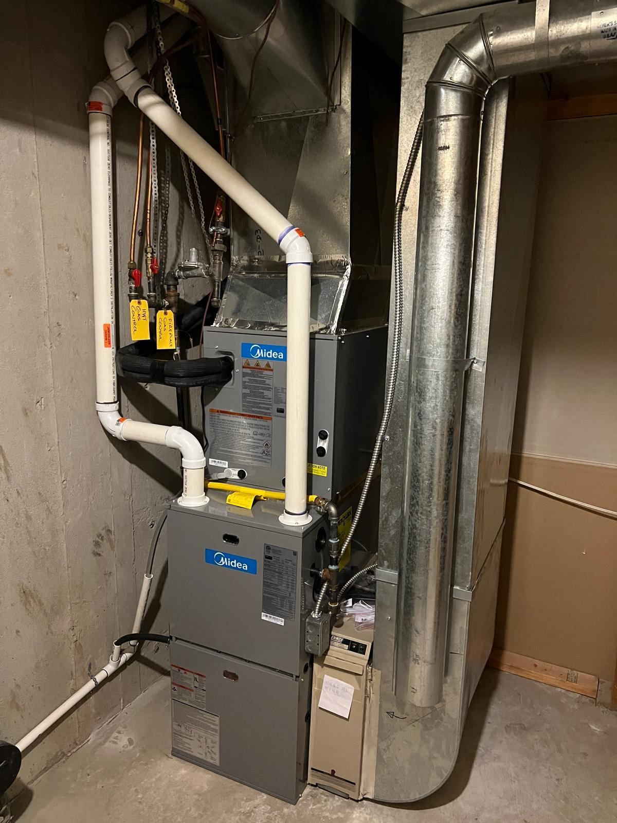 Midea high-efficiency furnace installed in basement with ductwork and PVC venting